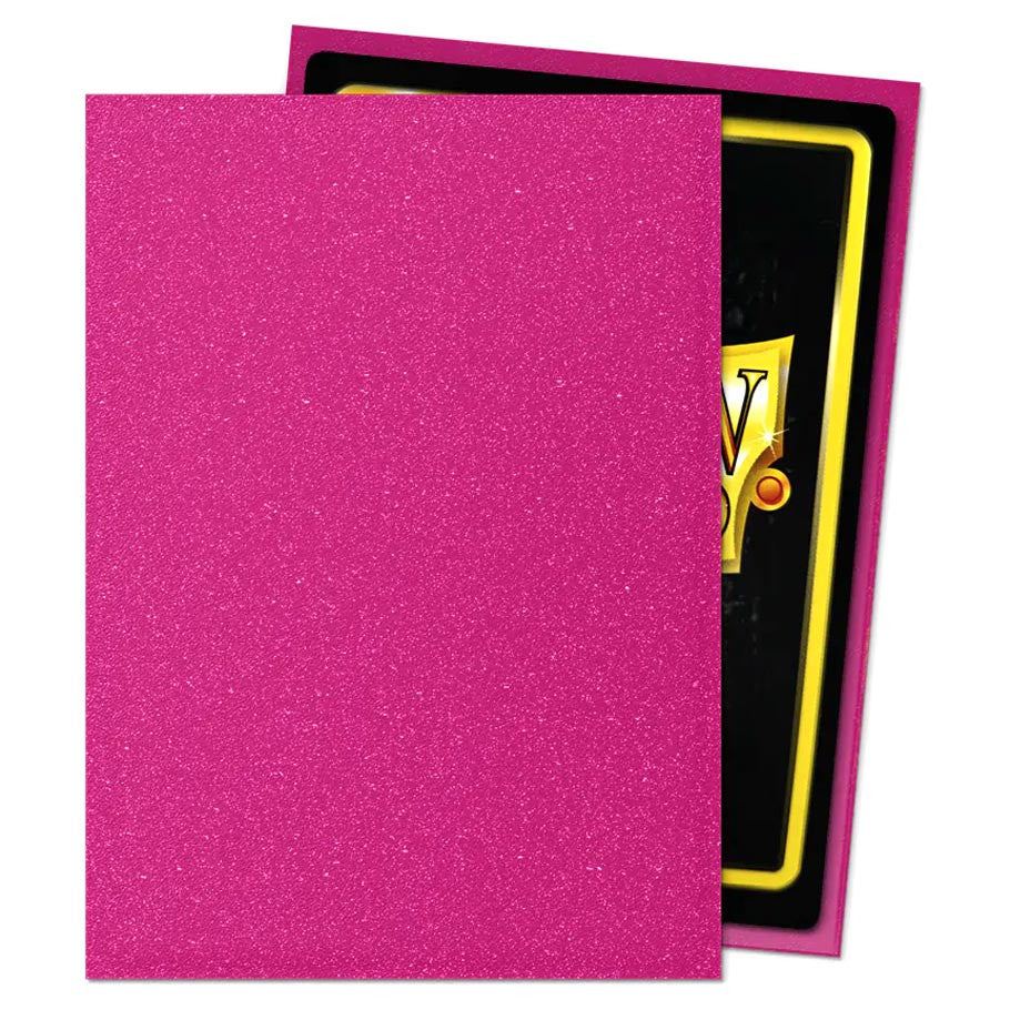 Dragon Shield Pink Sapphire - Matte Sleeves; bright fuchsia-pink glitter cardstock partly obscures a card, highlighting the vibrant, durable sleeves perfect for trading card games.