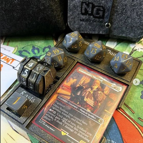 Nerd Gear Commander Essentials Kit: tabletop setup with foam tray, gray 20-sided dice, randomizer, Magic card, and felt pouch, ready for MTG session.